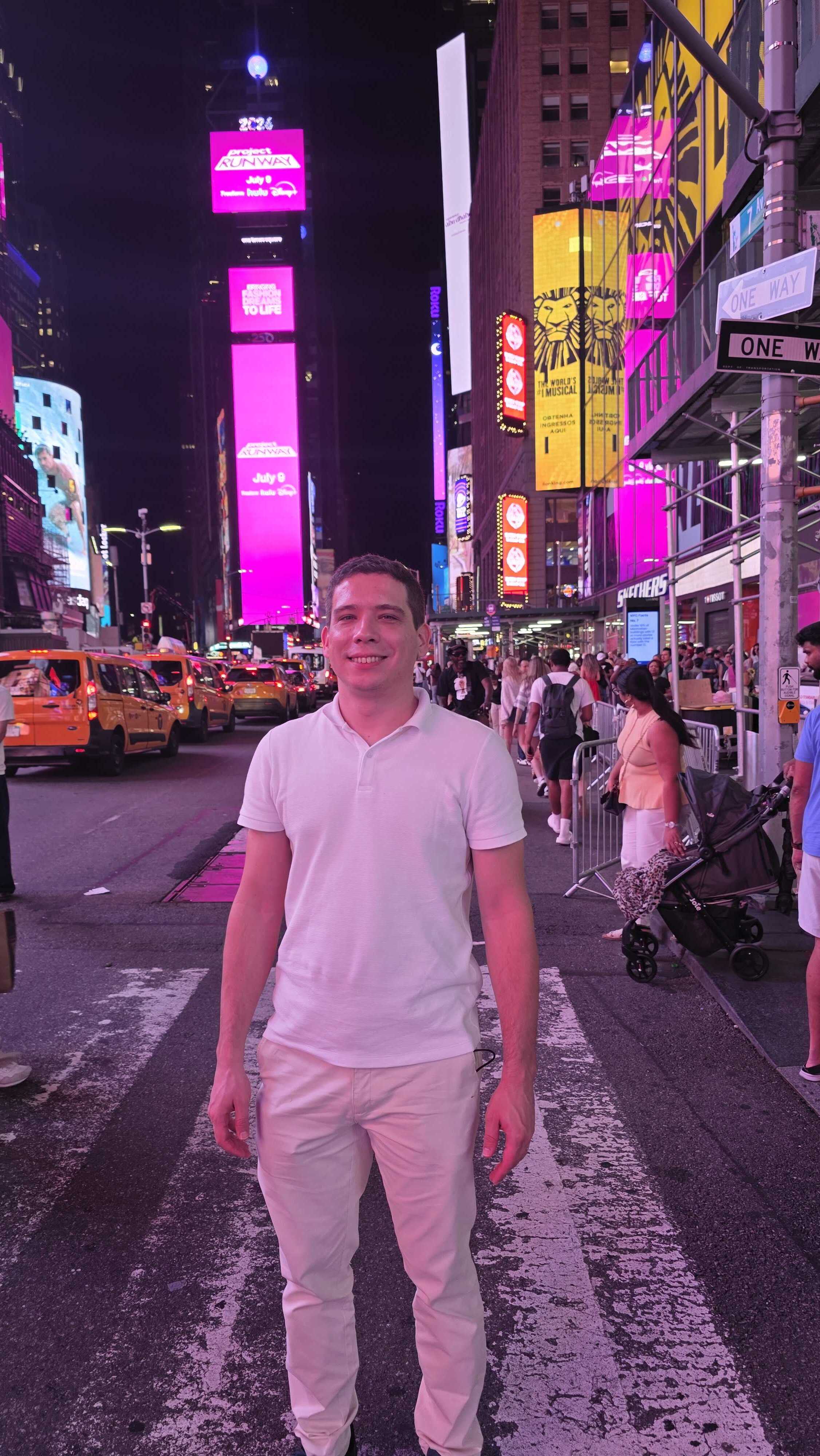 Eduardo Miguel em pé na Times Square, Nova York, à noite